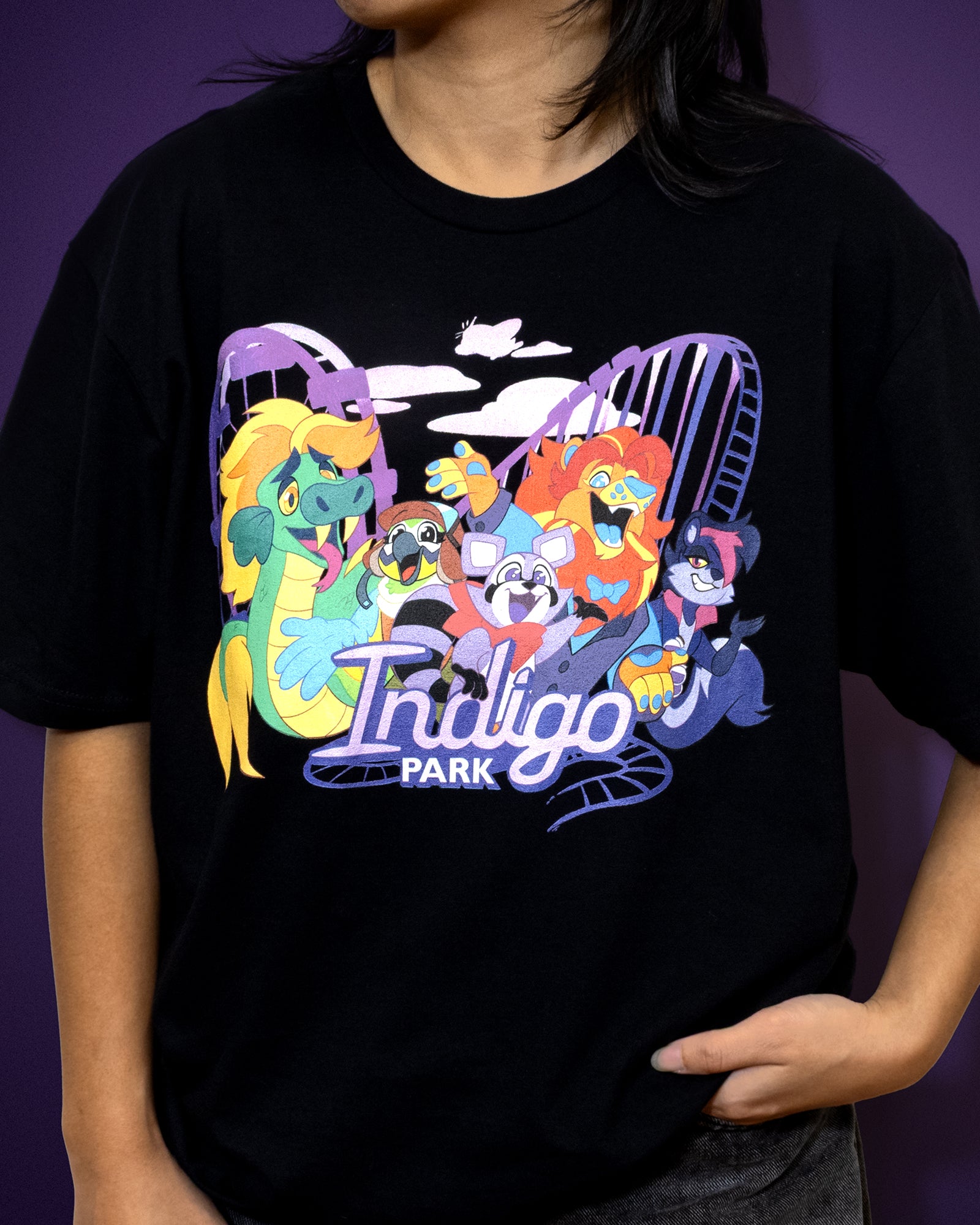 Person wearing a black t-shirt with colorful graphic design and 'Indigo Park' text on a purple background